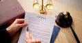 Close-up Of Judge Holding Document With Gavel