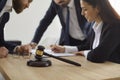 Close up of judge's gavel against background of lawyer and client signing legal contract.