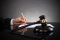 Close-up Of Judge Writing On Paper And Gavel At Desk Royalty Free Stock Photo