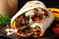 Close-up of juicy and savory shawarma wrap with tender sliced meat, fresh vegetables, and creamy sauce bursting out of the