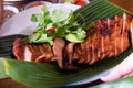 Close up juicy yummy fried sliced pork on green banana leaf , popular traditional Thai food