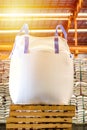 Close up of a jumbo bag on wooden pallet with background of bulk sugar bags