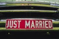 Close up of `just married` license plate with red background attached to chromed car grille. Wedding day concept. Royalty Free Stock Photo