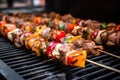 close-up of kebabs with variety of meat turning over a gas grill