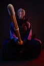 Close up. Kendo fighter wearing in an armor, traditional kimono, helmet, sitting, practicing martial art with shinai