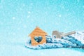 Close-up of a key and small keychain wooden house with a heart lying in a knitted scarf. Blue background. The concept of