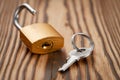 Close-up of a key and an unlocked padlock in golden color on a wooden background. Low angle view Royalty Free Stock Photo