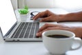 Close-up of keyboard of laptop computer with man hands using a mouse and coffee cup. Royalty Free Stock Photo