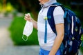 Close-up of kid boy with medical mask and backpack or satchel. Schoolkid on way to school. child outdoors. Back to