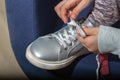 Close up kid girl hands tying shoelace on shoes before walk sitting on blue chair Royalty Free Stock Photo