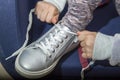 Close up kid girl hands tying shoelace on shoes before walk sitting on blue chair Royalty Free Stock Photo