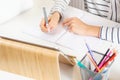 Close up of kid hands writing homework in notebook with pen. Child sitting at table with digital tablet computer at home Royalty Free Stock Photo