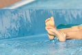 Close up of kid's feet, barefoot,in blue pool on sunny day at summer vacation. Happy little boy siting on the edge of the Royalty Free Stock Photo