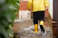 Close-up of kid wearing yellow rain boots and walking during sleet, rain and snow on cold day. Child in colorful fashion Royalty Free Stock Photo