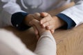 Close up kind young doctor holding hand or elderly patient.