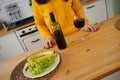 Close up of kitchen table with bottle, glass of red wine and fruits on plate. Body part of unrecognizable woman near Royalty Free Stock Photo