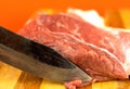 Close-up of a knife cutting raw red meat. Pork meat on a raznlock board. An old working butcher`s knife cuts a piece of red meat. Royalty Free Stock Photo