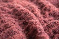 A close up of knitted soft woolen texture of coral color