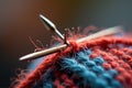 Close-up of knitting needles with red and blue yarn in focus Royalty Free Stock Photo
