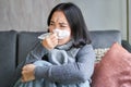 Close up of korean girl sneezing in napking, sitting at home in scarf, feeling unwell, concept of winter, heating cost