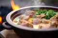 close-up of korma with steam, visible lamb chunks, in a clay bowl