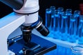 Close up of laboratory microscope with set of test tubes with blue liquid Royalty Free Stock Photo