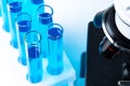Close up of laboratory microscope with set of test tubes with blue liquid Royalty Free Stock Photo