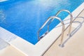 Close up of ladder stainless handrails (stairs) into the blue swimming pool. Vacation and sport concept. Royalty Free Stock Photo
