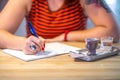 Close up of lady`s hand writing in notepad in coofee bar.