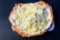 Close up of a langos, typical Hungarian food specialty, with sour cream and cheese on a white dish on a dark grey table, deep frie