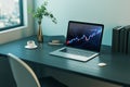 Close up of laptop with candlestick forex chart on screen placed on wooden office desk with coffee cup, books and vase. Window