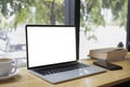 Laptop computer with empt display, smart phone, book and coffee cup on wooden table.