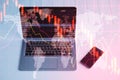 Close up of laptop on desktop with cellphone falling red forex hologram on blurry background. Stock crisis price drop down chart