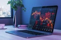 Close up of laptop on desktop with coffee cup, decorative plant, window with city view and falling red crisis forex chart on