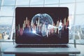Close up of laptop on desktop with glowing polygonal globe, blurry city view background and candlestick forex chart. Trade,