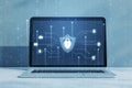 Close up of laptop with glowing blue padlock shield with digital coding on screen. Concrete wall background. Safety, programming