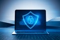 Close up of laptop with glowing shield hologram on screen. Blurry desktop background. Secure, protection, safety and web security