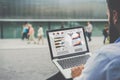 Close-up laptop with graphs, diagrams and charts on screen in hands of businessman sitting outdoors and working.