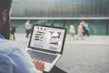 Close-up laptop with graphs, diagrams and charts on screen in hands of businessman sitting outdoors and working.