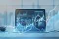 Close up of laptop at table with glowing candlestick forex chart on blurry wallpaper. Trade, finance and technology concept. Royalty Free Stock Photo