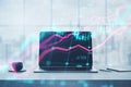 Close up of laptop at workplace with coffee cup and glowing forex index chart with grid on blurry background. Market, finance and Royalty Free Stock Photo