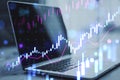 Close up of laptop at workplace with glowing candlestick forex chart on blurry background. Technology, trade and financial data Royalty Free Stock Photo