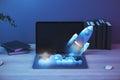 Close up of laptop at workplace with supplies and glowing flying rocket. Start up and launch concept. 3D Rendering