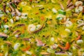 Close up of large portion of mixed seafood cooked with vegetables, available for sale at a street food market, selective focus