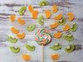 Close-up of a large round fruit candy on a background of slices of kiwi, mandarin Royalty Free Stock Photo