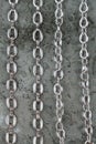 Close up of large shiny metalic silver chains on gray texture background top view