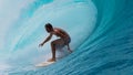 CLOSE UP: Large tube wave curls behind fearless sportsman surfing in Tahiti.