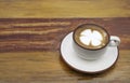 Close-up of Latte art or cappuccino white coffee cup with plate on wooden table with copy space.