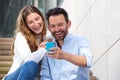 Close up laughing couple sitting on steps together with mobile phone Royalty Free Stock Photo