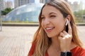 Close-up of laughing girl connecting her wireless earphones with finger in Sao Paulo modern metropolis